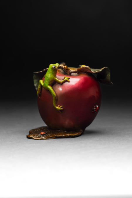 Photo of small bronze Sculpture featuring Tree Frog on two-toned apple with several insects