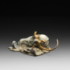 Photo of bronze sculpture of lizard on animal skull amongst flat rocky terrain